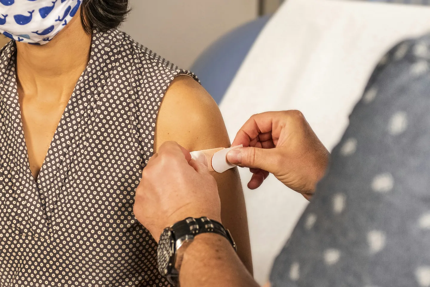Une infirmière applique une compresse sur le bras d'une patiente après un prélèvement sanguin.