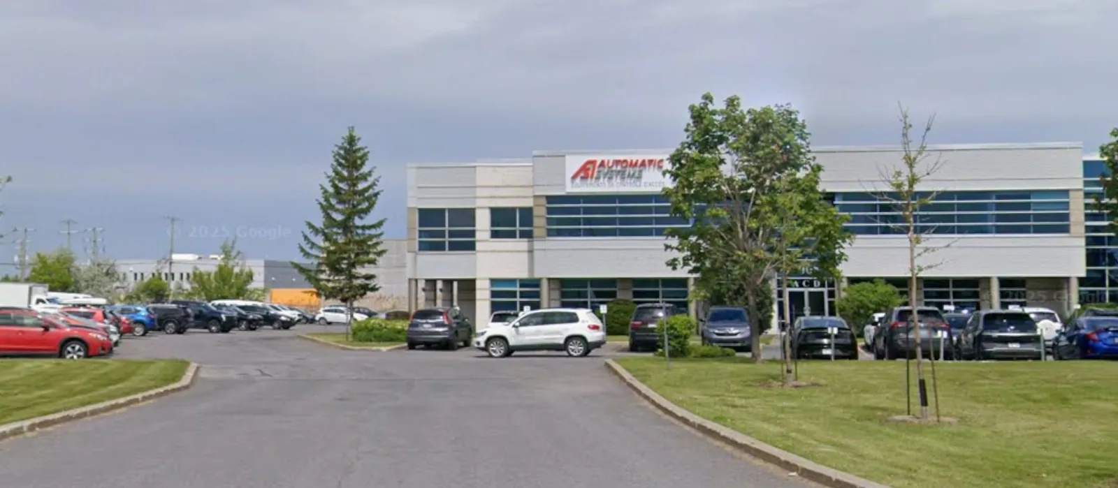 Le stationnement du 4005 boulevard Matte, avec une flèche indiquant la porte H, au bout du bâtiment à gauche.